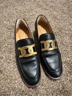 Tod's Black Leather women’s Slip-On Loafers with Gold Chain Link